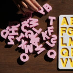 A white and yellow puzzle board, showing the English alphabet with pink capital letters