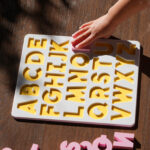 A white and yellow puzzle board, showing the English alphabet with pink capital letters